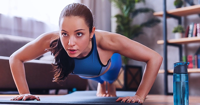 A lady performing push-ups | Trainest