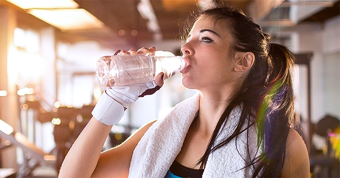 A fit woman drinking water | Trainest