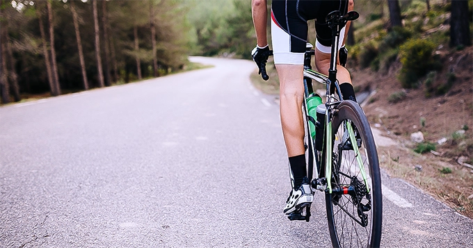 A cyclist riding uphill | Trainest