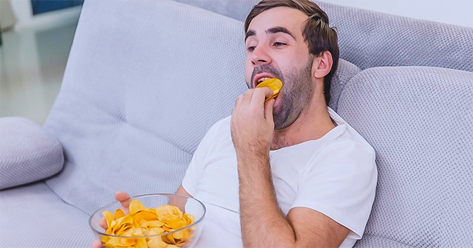 A couch potato eating chips | Trainest 