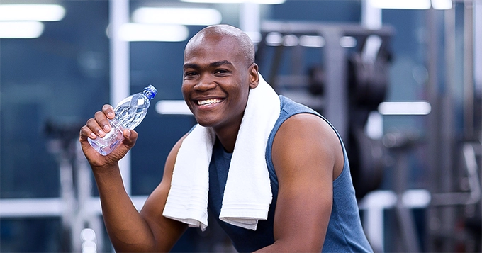 A fit man drinking water in the gym | Trainest 