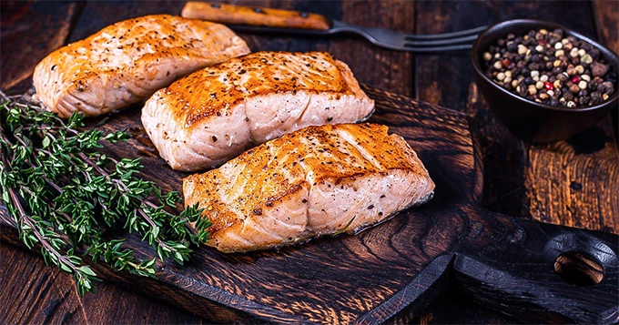 Grilled salmon filets on a chopping board | Trainest 