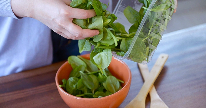 Raw spinach being put into a bowl | Trainest 