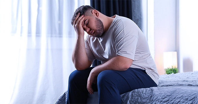 An overweight man looking exhausted | Trainest 