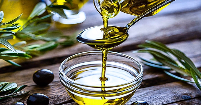 Olive oil poured onto a spoon and into a bowl | Trainest 