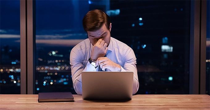 Someone exhausted and in front of a computer | Trainest 