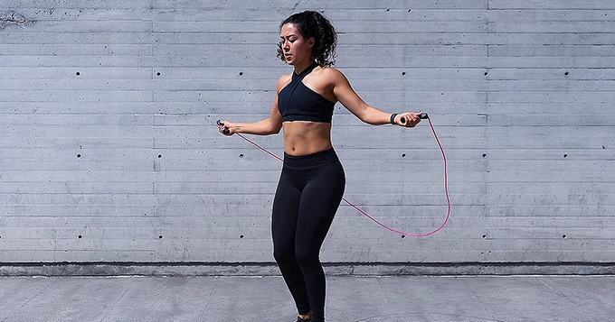 A woman exercising with a jump rope | Trainest 