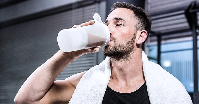 A fit man drinking a protein shake while in the gym | Trainest 