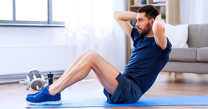 A man doing crunches in the living room | Trainest 