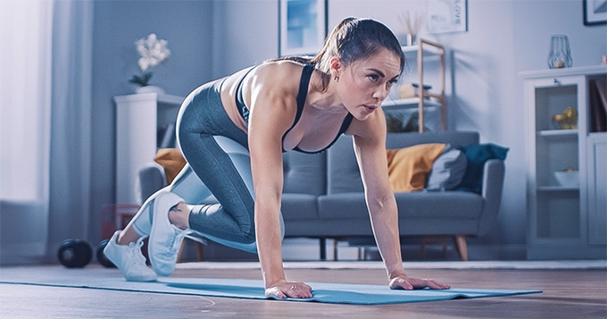 A woman performing mountain climbers at home | Trainest 