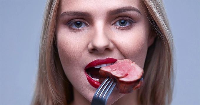 A lady eating a big chunk of steak | Trainest 