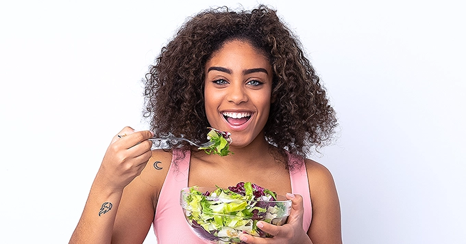 A woman eating a bowl of salad | Trainest 