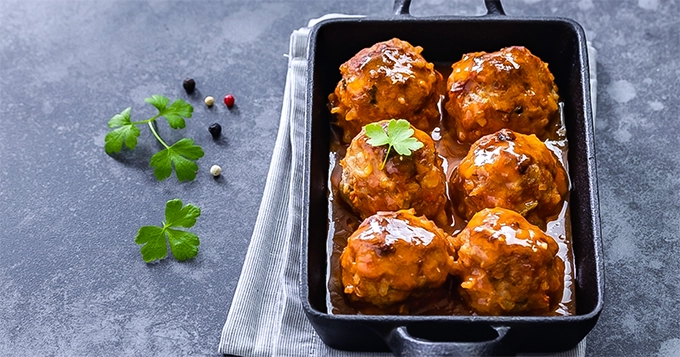 Meatballs with red sauce in a baking tray | Trainest 