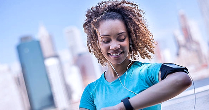 An exercising woman looking at her fitness tracker | Trainest 