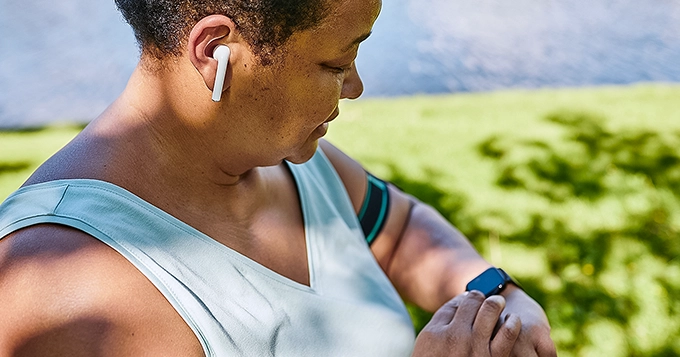 A woman wearing a fitness tracker and exercising outdoors | Trainest 