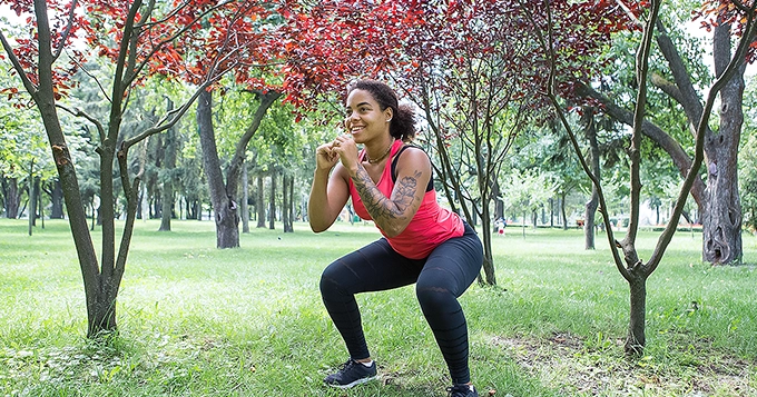 Someone exercising outdoors, doing squats | Trainest 