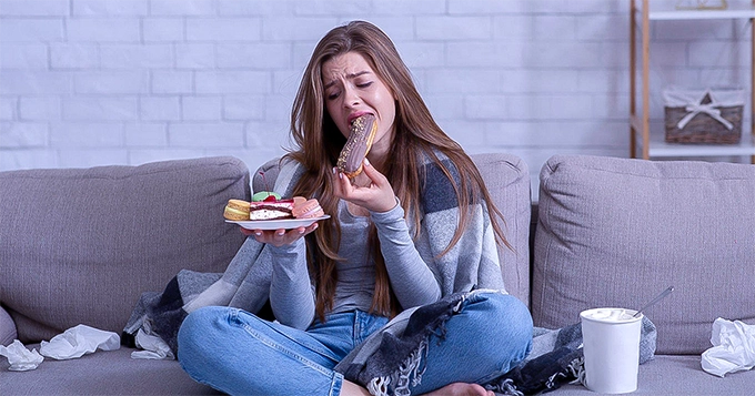 A woman engaged in emotional eating | Trainest 