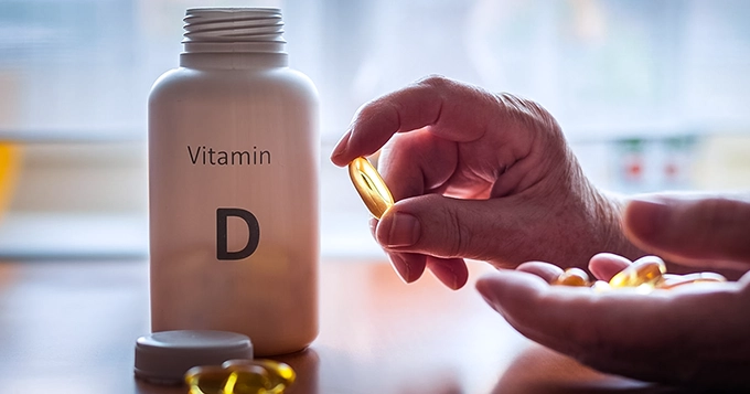 Someone taking Vitamin D softgels from a bottle | Trainest 