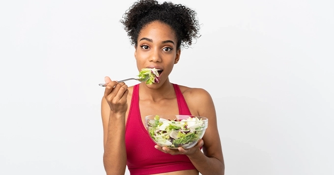 A fit woman eating a salad | Trainest 