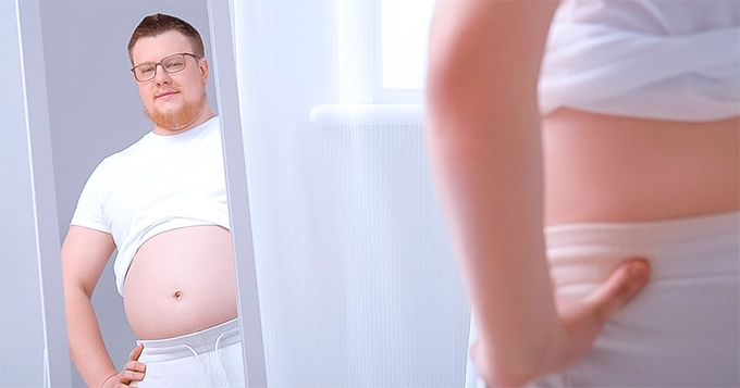 An overweight man sneering at himself | Trainest 
