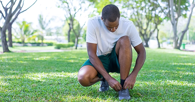 A man lacing up his running shoes in the park | Trainest 