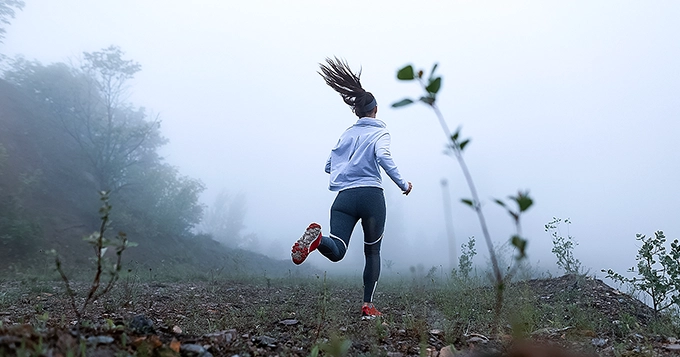 A woman running on a rocky trail | Trainest 