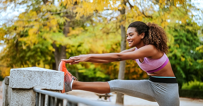 A woman wearing workout clothes stretching her leg | Trainest 