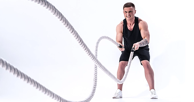 A man exercising with battle ropes | Trainest 