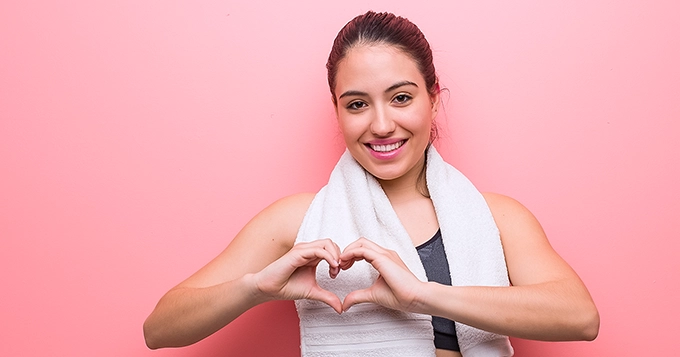 A woman forming a heart shape with her hands | Trainest 