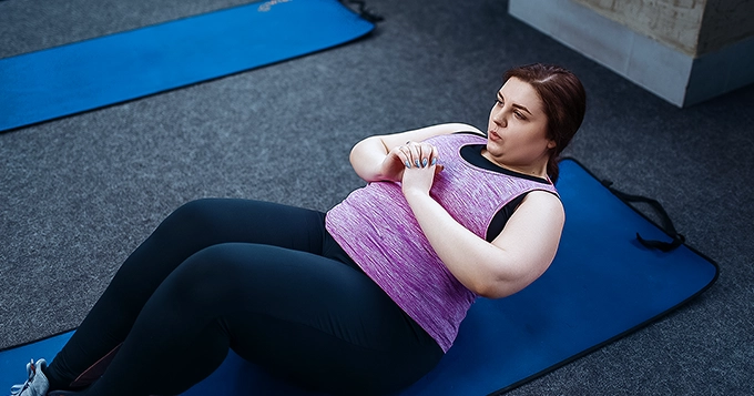 A heavyset woman exercising in a gym | Trainest 