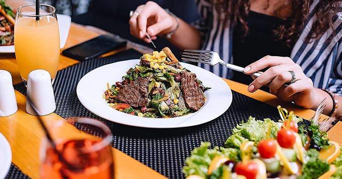 A woman eating a steak salad | Trainest 