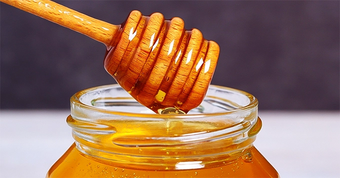 A honey dipper on a jar of honey | Trainest 