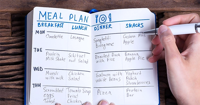 A person writing a meal plan | Trainest 