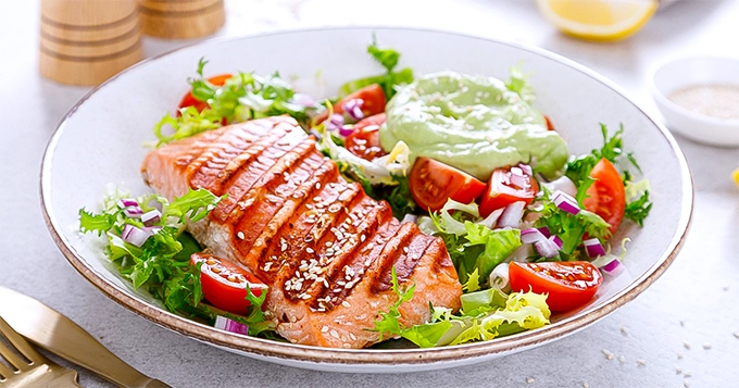 A plate of grilled salmon and a salad | Trainest 