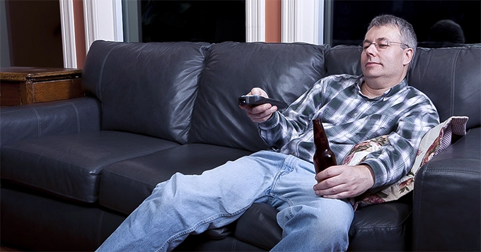 A man on the couch with a beer in hand | Trainest 