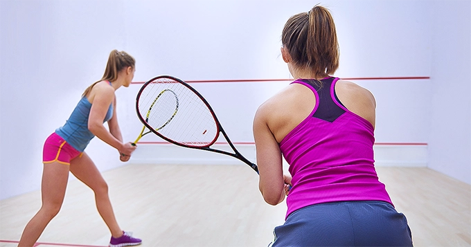 Two women playing squash | Trainest 