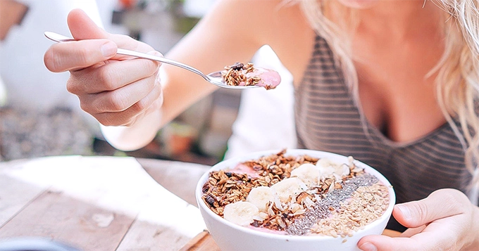 A woman eating a bowl of cereals | Trainest 