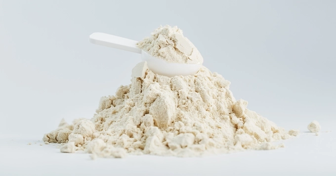 A scoop on top of a mound of protein powder | Trainest 