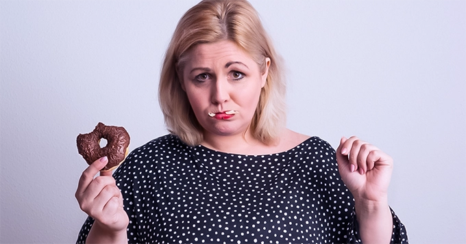 A woman holding a chocolate donut | Trainest 