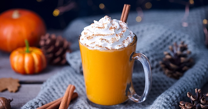 A mug of pumpkin spice latte topped with whipped cream | Trainest
