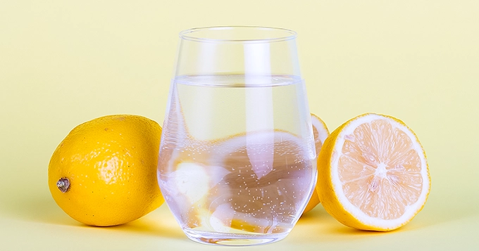 A glass of sparkling water with lemons | Trainest
