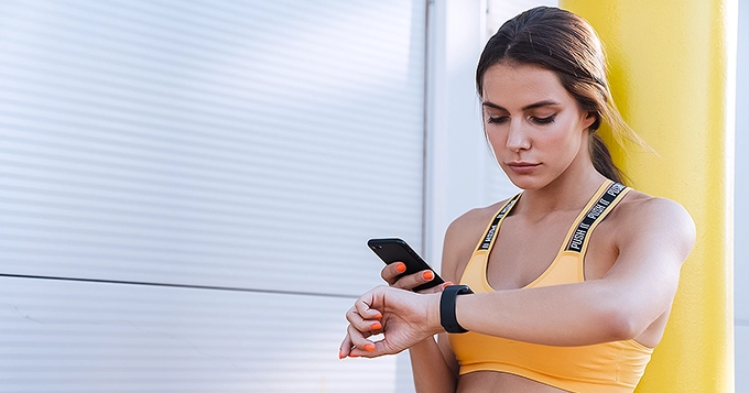 A fit woman tracking her workout on her watch and phone | Trainest
