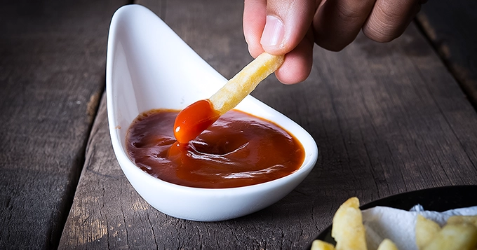 A piece of french fries being dipped in ketchup | Trainest 