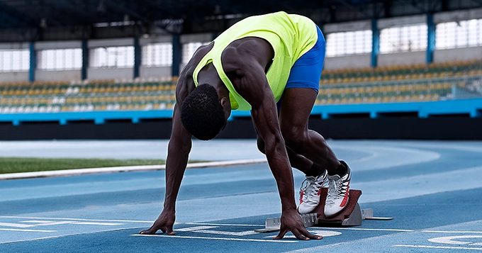 A runner setting up at the starting line of a track | Trainest 