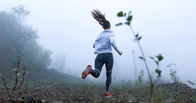 A woman running on rocky terrain | Trainest 