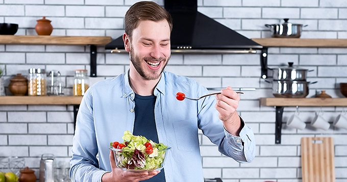 Someone eating a bowl of salad in the kitchen | Trainest 