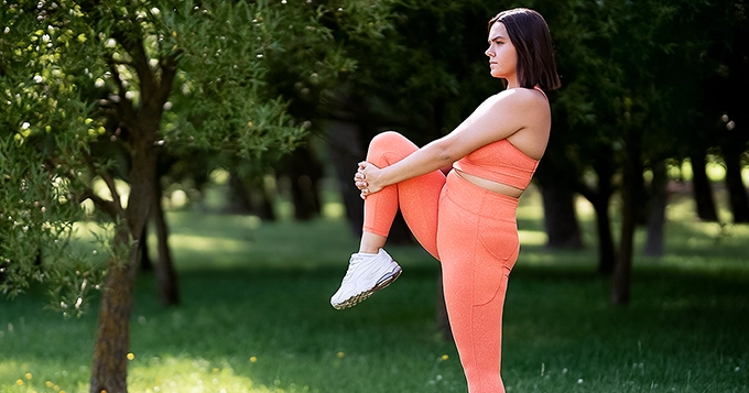 A woman outdoors, stretching her thighs | Trainest 