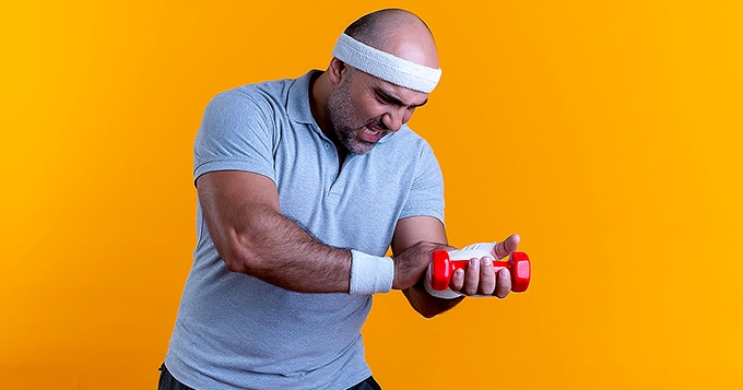 A man holding onto his wrist while lifting a dumbbell | Trainest 