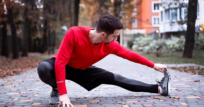 A man outdoors stretching his leg, preparing for a run | Trainest 