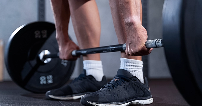 Someone getting ready to lift a barbell off the floor | Trainest 